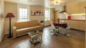 Sala de estar moderna com sofá, mesa de centro e área de jantar com cadeiras.