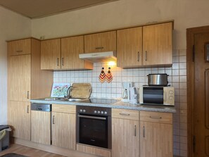 A kitchen with wooden cabinets, a Bosch dishwasher, a microwave, and a coffee maker. - Landhaus Nahe Sababurg Schloss (Trendelburg)