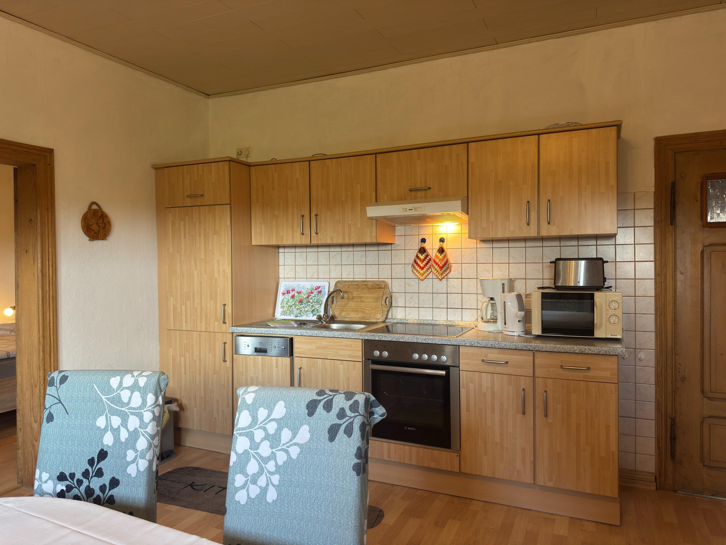 A kitchen with wooden cabinets, a Bosch oven, a coffee maker, and a toaster.