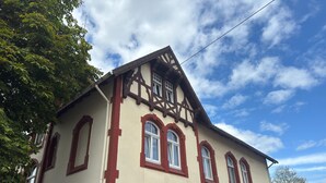 A two-story building with a traditional architectural style, featuring a gabled roof and multiple windows with red trim. - Landhaus Nahe Sababurg Schloss (Trendelburg)