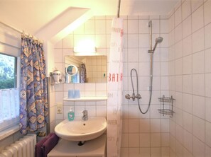 A bathroom with a sink, mirror, shower, and a window with curtains. - Holiday Home Near the Forest in Oppenau (Oppenau)