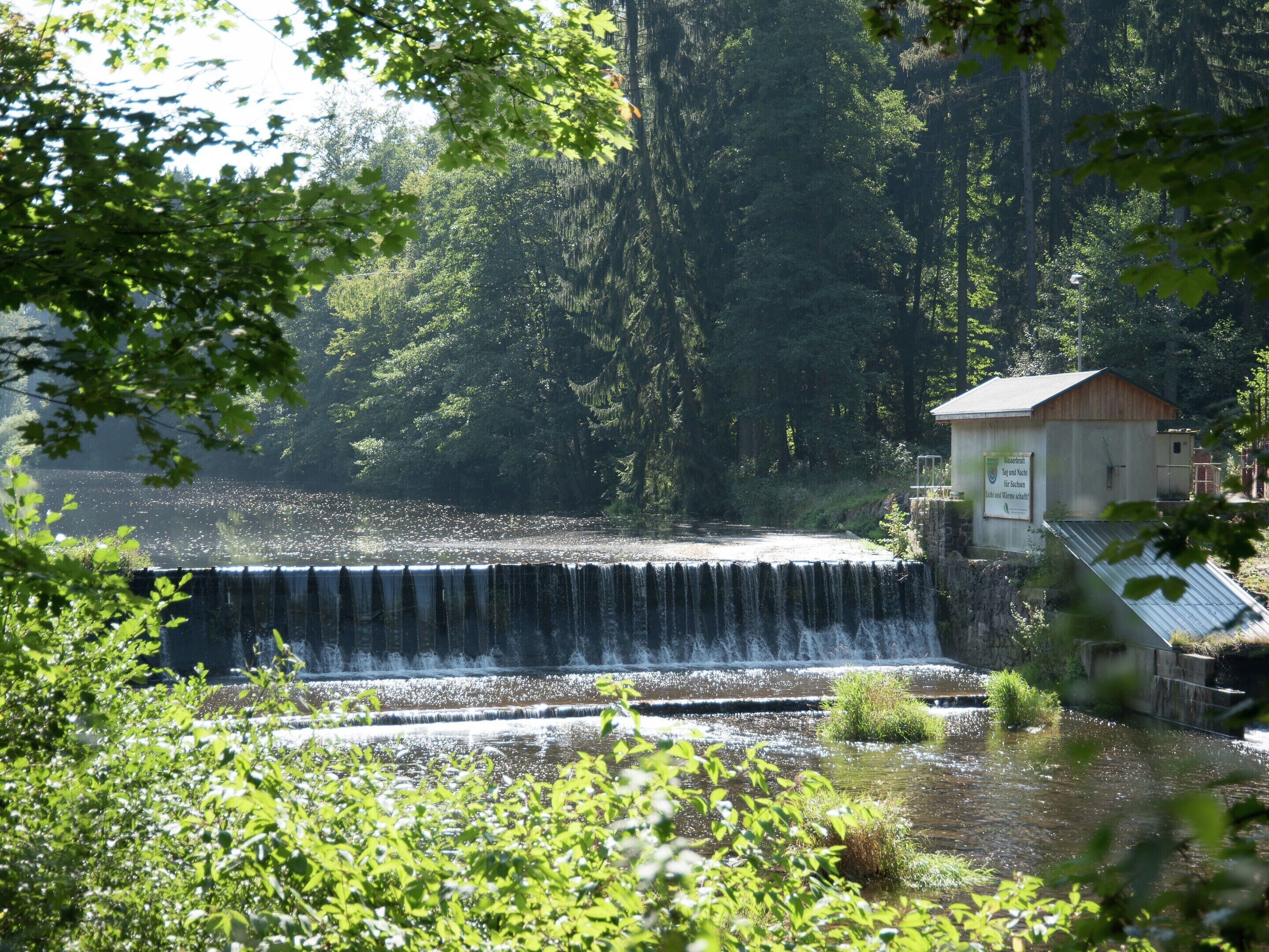 A waterfall with a small building nearby.