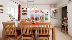 A dining area with a wooden table and chairs, a chandelier, and a view through glass doors to an outdoor patio. - Comfortable Holiday Home in Saxony With Terrace (Oederan)