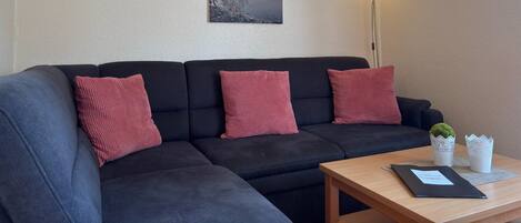 Una sala de estar moderna con un sofá modular, una mesita y una lámpara de pared.