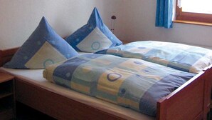 A bed with blue and white bedding, a wooden headboard, and a window with blue curtains. - Holiday Home in Germany With Garden Terrace (Brakel)