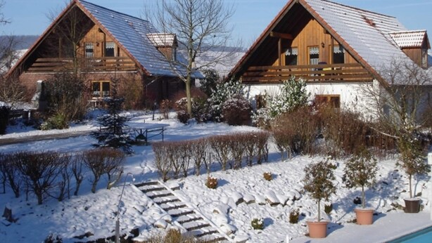 A wooden cabin with a sloped roof, surrounded by snow-covered ground and trees. - Holiday Home in Germany With Garden Terrace (Brakel)