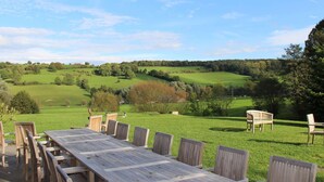 A wooden table and chairs set outdoors with a view of rolling green hills and trees. - Superb Holiday Home With Barbecue (Plombieres)
