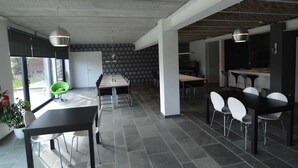 A modern kitchen with a dining area, featuring a long table with chairs, pendant lights, and a patterned backsplash. - Superb Holiday Home With Barbecue (Plombieres)