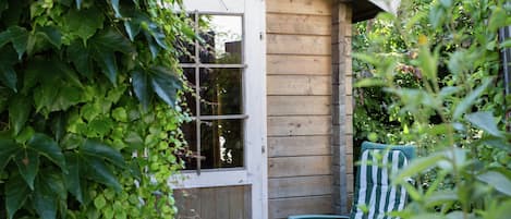 A wooden cabin with a door, a window, and a chair.