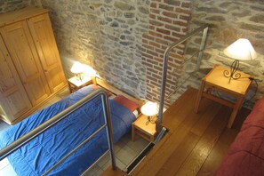 Ein Schlafzimmer mit Etagenbett, einem Holzschrank, einem kleinen Tisch mit Lampe und einer Ziegelwand.