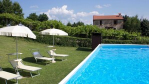A swimming pool with lounge chairs and umbrellas, surrounded by a grassy area and trees. - Stay With Balcony Views (Casalfiumanese)