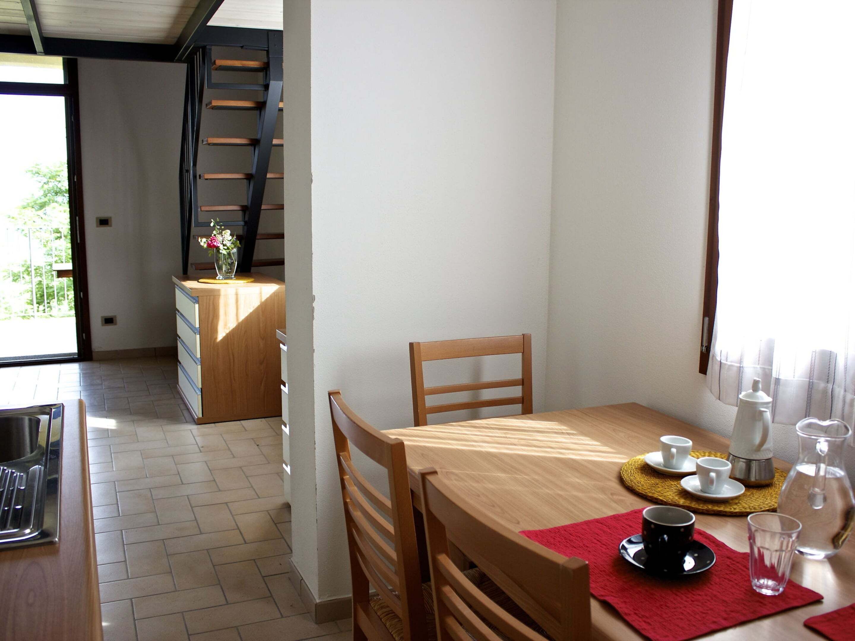 A dining area with a wooden table, chairs, and a kitchen area with a counter and cabinets.