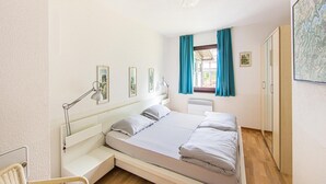 Un dormitorio con cama, escritorio, silla y ventana con cortinas.