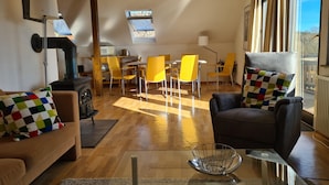 Un amplio salón con chimenea, sillones amarillos, un sofá y una mesa de comedor.