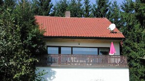 Ein Haus mit rotem Ziegeldach, einem Balkon mit Holzbalkon und einer Satellitenschüssel.