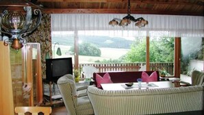 Ein gemütliches Zimmer mit Holzboden, einem Fernseher, einer Couch und einem Tisch.