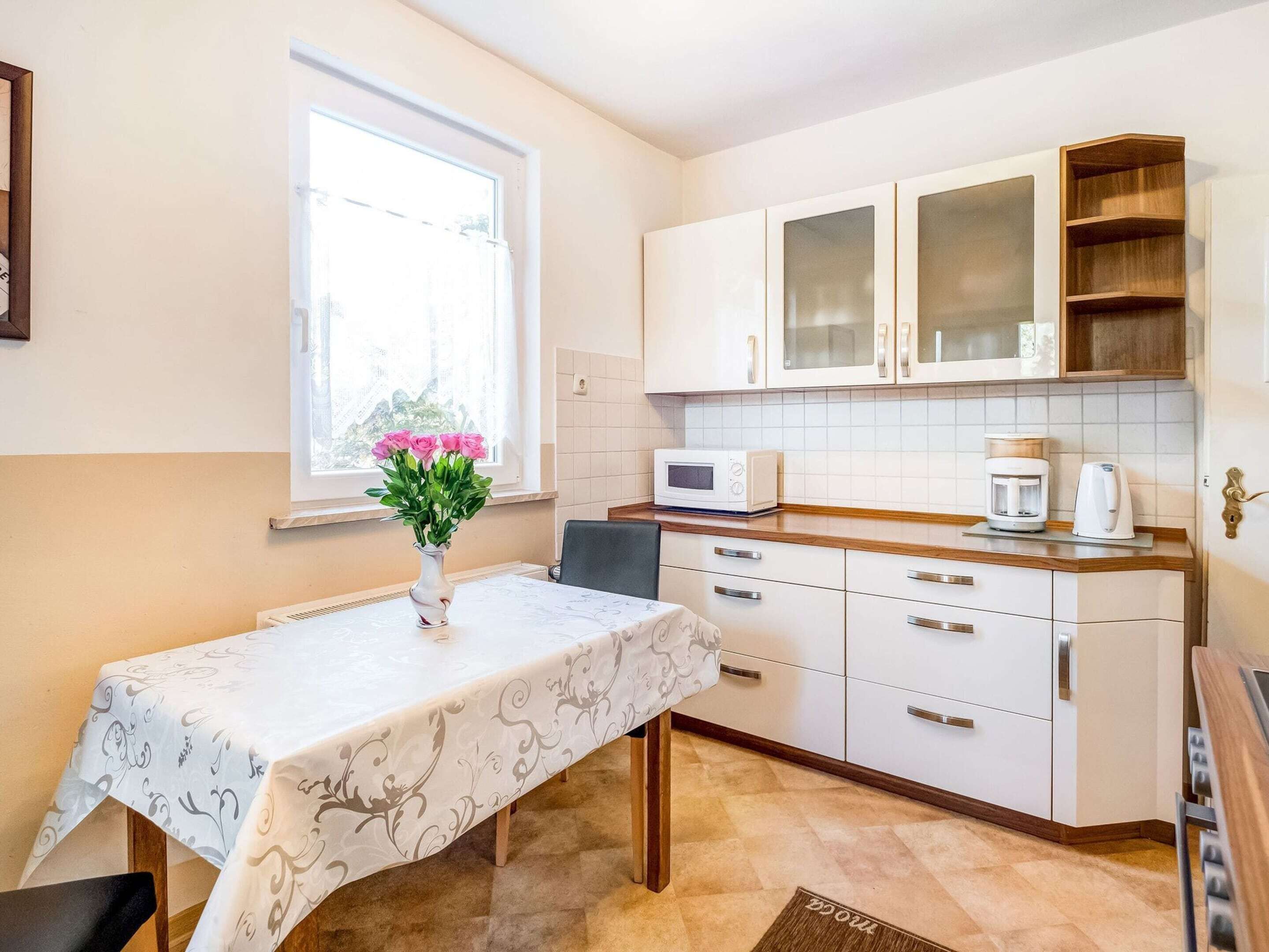 A compact kitchen with white cabinets, a microwave, a coffee maker, and a window with a view.