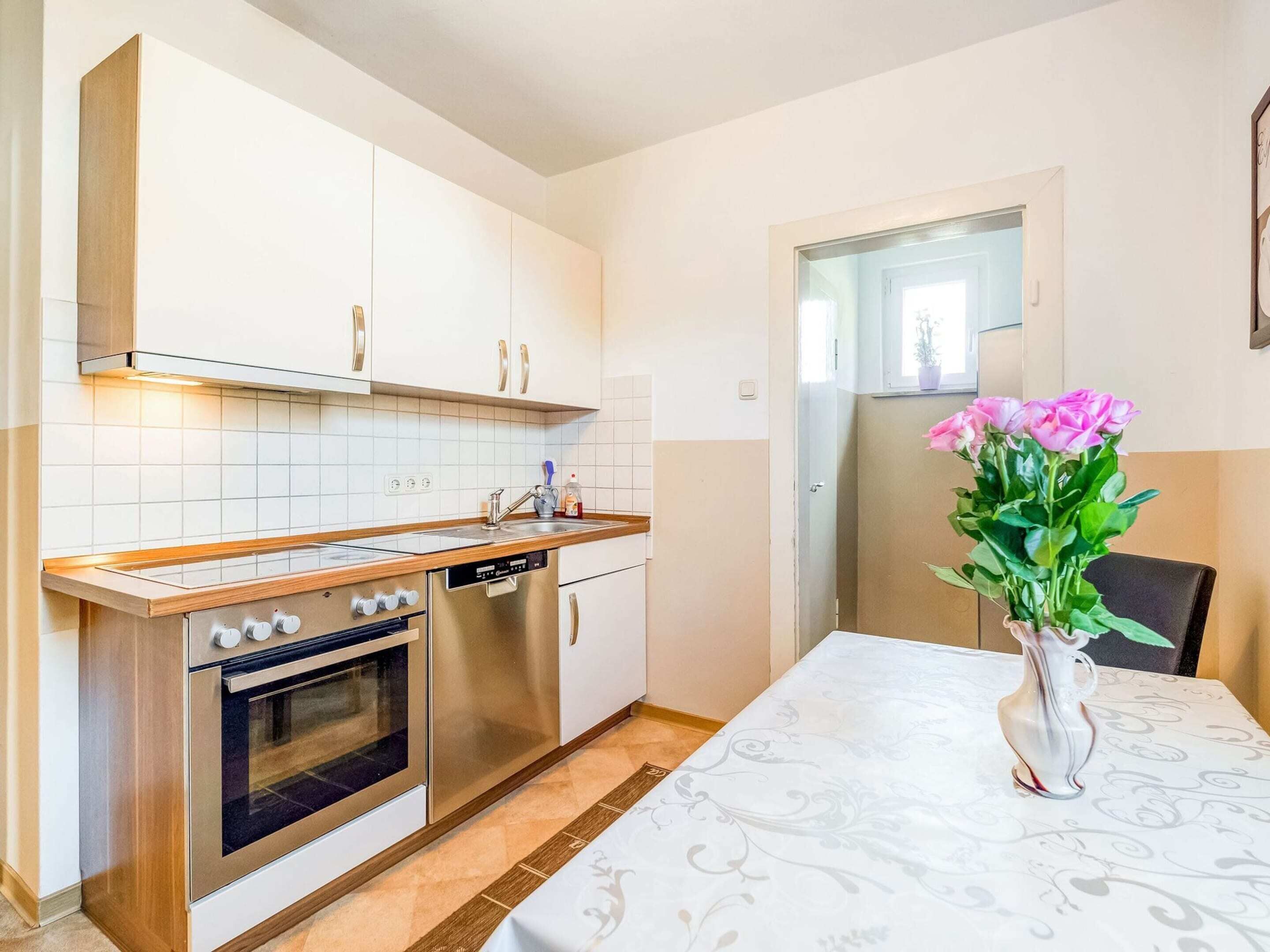 A modern kitchen with white cabinets, stainless steel appliances, and a dining table with a white tablecloth.