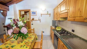 A kitchen with wooden cabinets, a gas stove, and a dining table with a sunflower tablecloth.