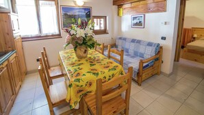 A cozy room with a wooden table and chairs, a sofa, and a bed.