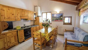 A kitchen with wooden cabinets, a dining table with chairs, a stove, and a refrigerator.