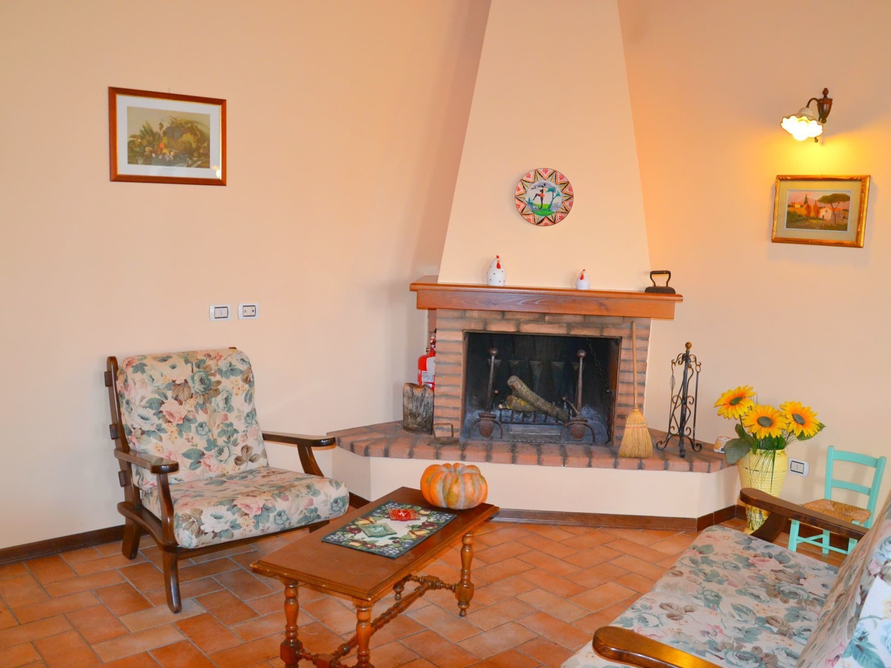 A cozy living room with a fireplace, floral-patterned furniture, and decorative items.