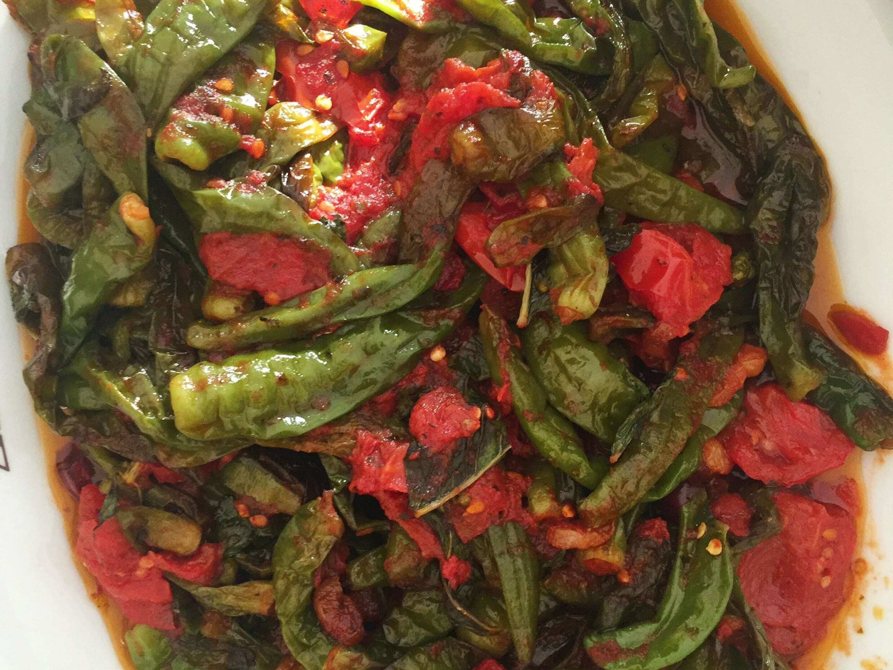 Une vue rapprochée d’un plat contenant des légumes verts et des tomates rouges.