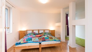 A bedroom with a wooden bed, two bedside lamps, and a window with curtains.