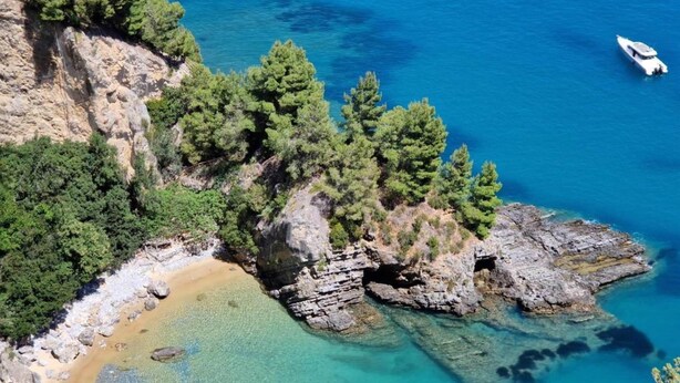 Eine Küstenlandschaft mit felsigen Klippen, klarem türkisblauem Wasser und einem Sandstrand.