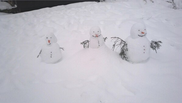 Tres muñecos de nieve en un paisaje nevado.