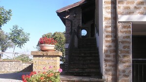 A stone staircase leading to a building entrance with a metal gate. - Belvilla by OYO I Granai (Bagnoregio)
