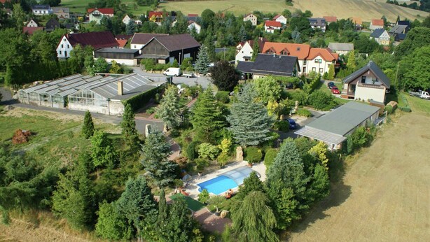 An aerial view of a residential area with houses, a swimming pool, and a greenhouse. - Gemutliches Ferienhaus in Sebnitz (Sebnitz)