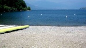 A pebbled beach with a yellow kayak and buoys in the water. - Belvilla by OYO Bilo Garden Due Bis (Cannobio)