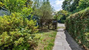 A stone pathway leading through a lush garden with dense foliage on both sides. - Belvilla by OYO Studio Garden Uno Bis (Cannobio)