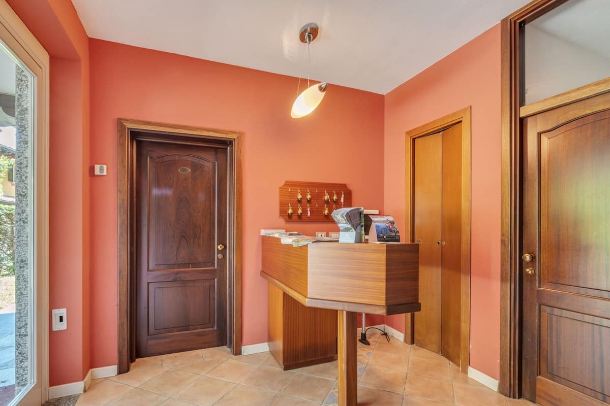 A hallway with a wooden reception desk, a door, and a wall-mounted light fixture.