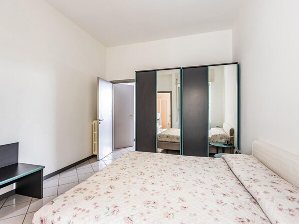 Une chambre à coucher comprenant un lit, une commode, un miroir et une porte donnant sur une autre pièce.