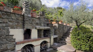 A stone building with a fireplace, a staircase, and potted plants.