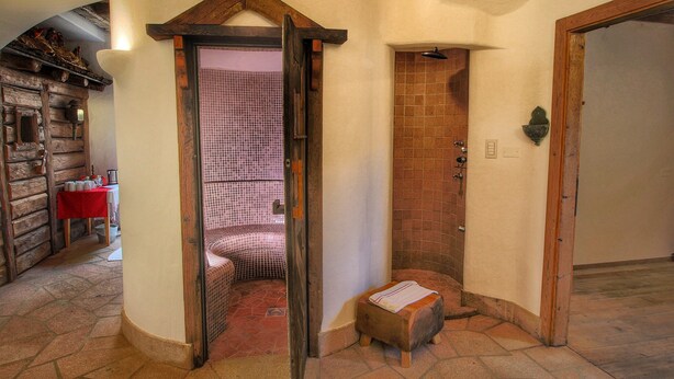 A bathroom with a shower, a wooden bench, and a tiled floor. - Dreamy Cottage in Bellamonte Italy with Hot Tub (Predazzo)