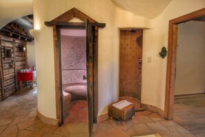 Une salle de bain avec une douche, un banc en bois et un sol carrelé.