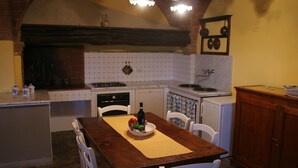 A kitchen with a wooden table, white chairs, a stove, and a sink. - Romantic Farmhouse near Medieval Village of Montaione (Montaione)