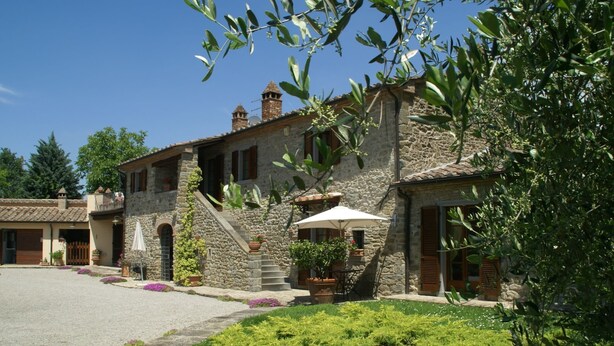 A stone building with a courtyard, a staircase, and a large umbrella. - Holiday Home in Cortona (Cortona)