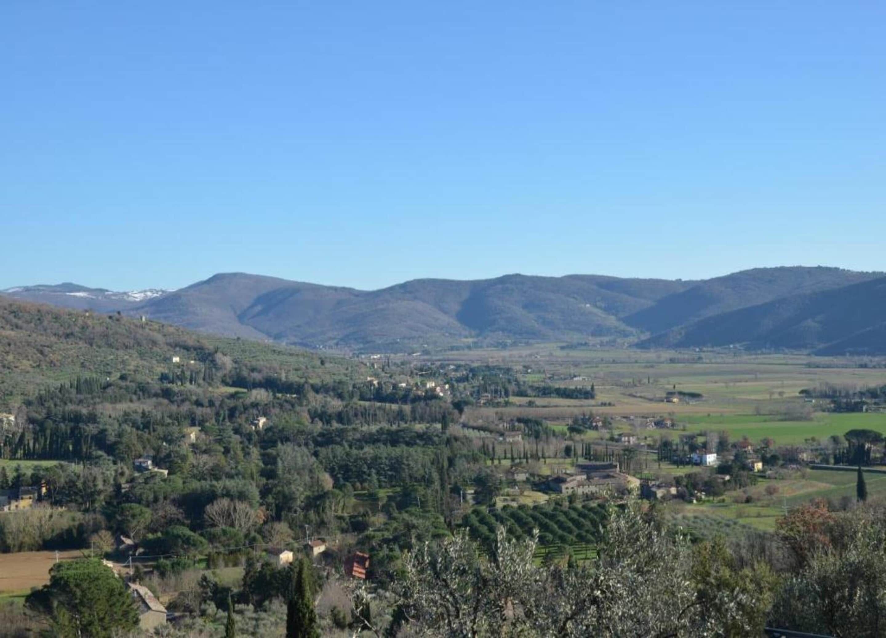 Vista panorámica de un paisaje montañoso con edificios dispersos y vegetación.