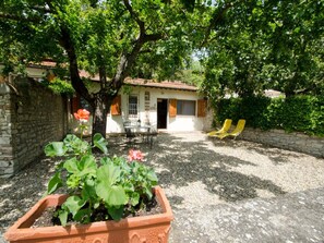 Relax in a serene outdoor space with a herb garden, stone wall, and comfortable lounge chairs.
