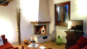 Een gezellige woonkamer met een open haard, een televisie en comfortabele zitplaatsen.