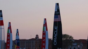 A marina with sailboats, including one with 'ORACLE' and 'PUMA' logos, and a building with a clock tower in the background. - Sun Drenched Seaside Holiday Home near Venice (Rosolina)