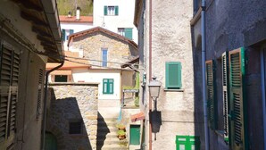 A narrow street with stone buildings, green shutters, and a staircase leading to a higher level. - Holiday Home in Sesta Godano With BBQ (Sesta Godano)