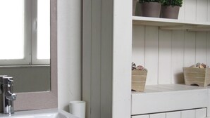 A bathroom with a white sink, a mirror, a window, and shelves with potted plants and baskets. - Namur Mansion by the Meus (Hastiere)