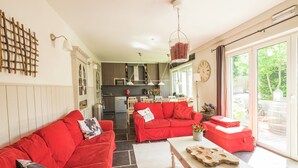 A spacious living area with a red sofa set, a white coffee table, and a kitchen in the background. - Namur Mansion by the Meus (Hastiere)