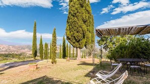 A garden with a pergola, outdoor seating, and tall trees. - Belvilla by OYO Macetona - Suite (San Casciano dei Bagni)
