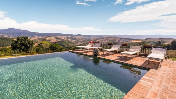 A clear swimming pool with lounge chairs and a view of distant mountains. - Belvilla by OYO Macetona - Suite (San Casciano dei Bagni)
